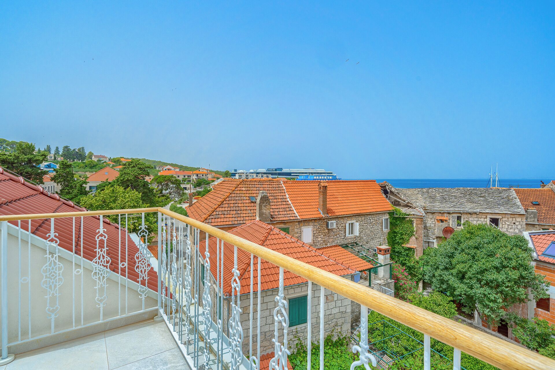 Un pueblo costero con tejados rojos tradicionales, edificios de piedra y una vista despejada del mar.