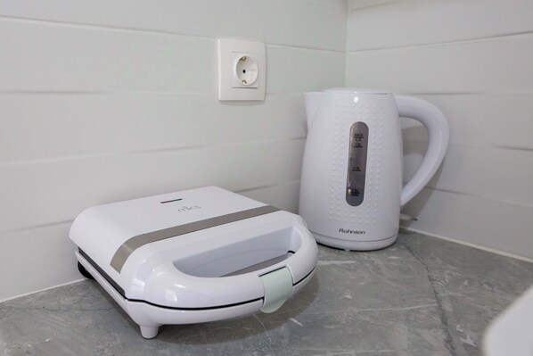Een witte elektrische waterkoker en een witte elektrische tandenborstel op een marmeren aanrecht.