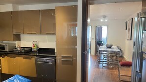 A modern kitchen with stainless steel appliances, wooden cabinets, and a dining area with a table and chairs.