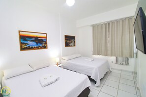 Een hotelkamer met twee eenpersoonsbedden, een flatscreen televisie, een kachel en twee ingelijste foto's aan de muur.