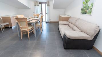 Una sala de estar moderna con sofá, mesa de comedor, sillas y zona de cocina.