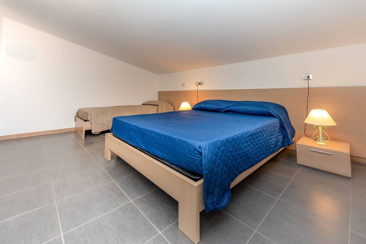 A modern bedroom with a large bed, two bedside tables, and a nightstand.