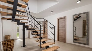 A modern staircase with wooden steps and black metal railings, leading to a room with a large mirror and a door. - Family Villa Di with pool (Malinska)