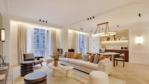 A spacious living room with a sofa, coffee table, and ottoman, a dining area with a table and chairs, and a kitchen with a counter and cabinets. - LUXE- A PERFECT BLEND OF CHARM, COMFORT & MODERNITY SAINT GERMAIN- RUE DE RENNES (Paris)