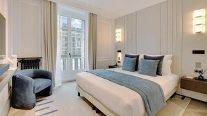 A modern hotel bedroom with a large bed, a seating area, and a view of the city through the window. - LUXE- A PERFECT BLEND OF CHARM, COMFORT & MODERNITY SAINT GERMAIN- RUE DE RENNES (Paris)