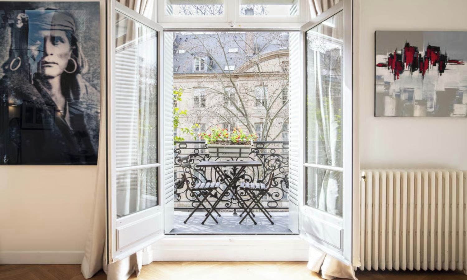 A room with a view of a balcony, a radiator, and a framed artwork.