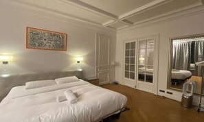 Quarto de hotel com uma cama grande, um espelho, um guarda-roupa e um quadro na parede.