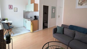 A modern living room with a grey sofa, a round glass coffee table, and a dining area with a white table and chairs. - Cozy, quiet and super centrally located! Apartment Napoleon in Meissen. (Meißen)