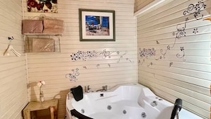 A bathroom with a white bathtub, wooden beams, a framed picture on the wall, and decorative wall stickers. - Comfort in the center of Upper Galilee, Pets are welcome, with green, spacious. (Mishmar HaYarden)