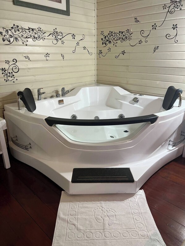 A corner bathtub with a black seat, a footrest, and a small control panel. - Comfort in the heart of Upper Galilee; pets welcome; green and spacious. (Mishmar HaYarden)