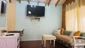 A living room with a TV mounted on the wall, a sofa, a small table, and a chair. - Comfort in the center of Upper Galilee, Pets are welcome, with green, spacious. (Mishmar HaYarden)