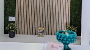 A reception area with a wooden panel wall, a sign with 'Lies' and a sun design, a small plant, a QR code, and a teal decorative item. - Lues Rooms (Ragusa)