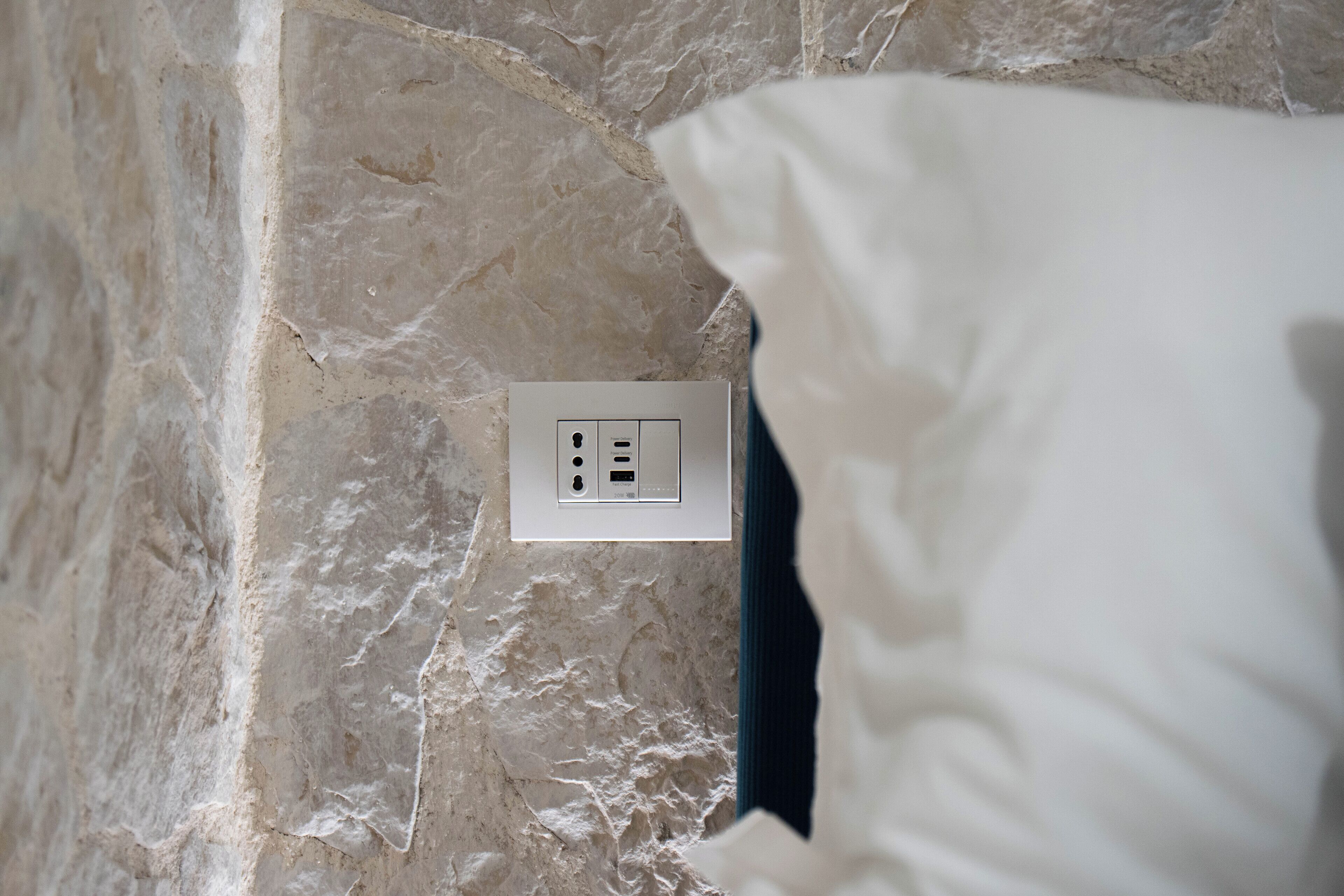 Un mur de marbre avec une prise électrique et un coussin blanc.