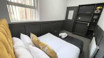 Une chambre d’hôtel avec un lit, une fenêtre, une armoire et un radiateur.
