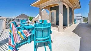 A covered outdoor seating area with a table and chairs, a potted plant, and a view of neighboring buildings. - 🌞The Rooftop on 30A | Stunning Rooftop Gulf Views | Easy Beach Access🌞 (Santa Rosa Beach)