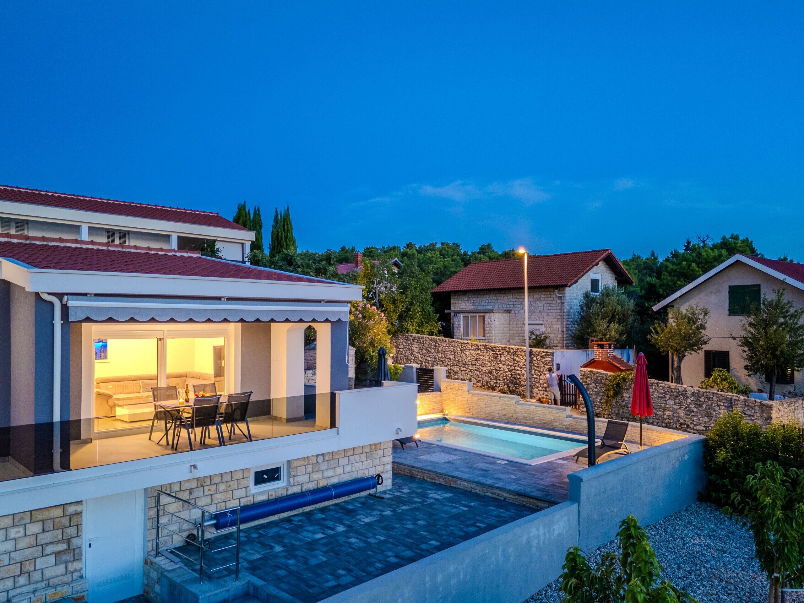 A modern house with a swimming pool, outdoor seating, and a stone wall.