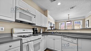 A modern kitchen with white cabinetry, a gas stove, a microwave, and a dishwasher.