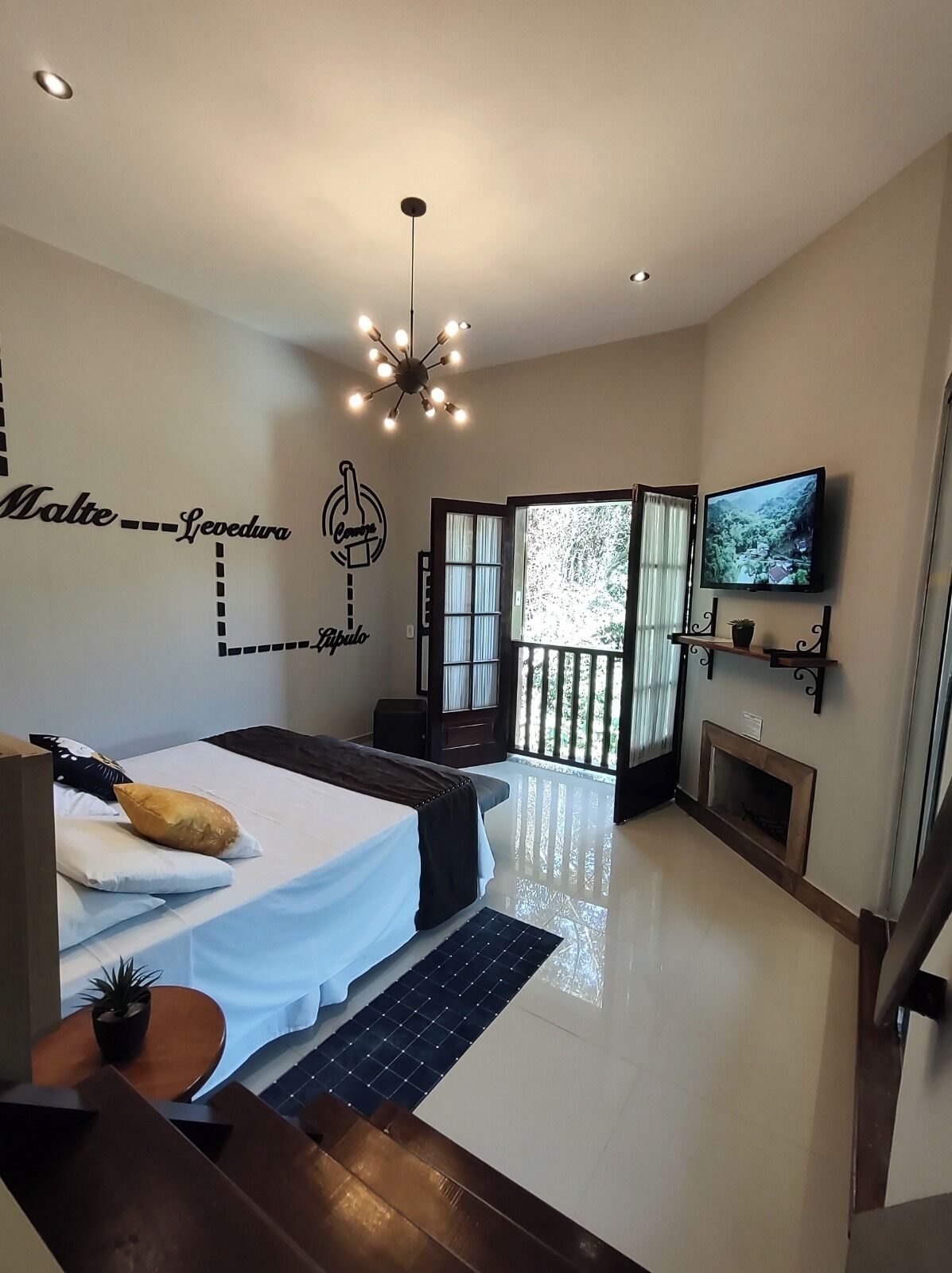 A modern bedroom with a bed, a TV, a fireplace, and a balcony with a view.
