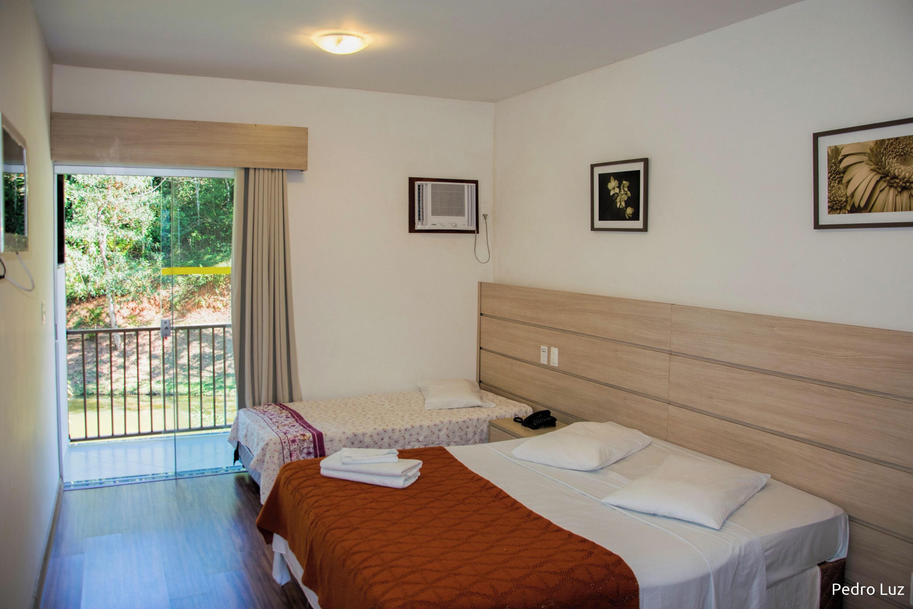 A hotel room with two beds, a balcony, a telephone, and a framed picture on the wall.