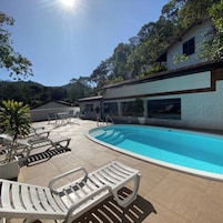 Zona de piscina con sillas de descanso y un edificio con amplias ventanas.