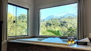 A room with a large window, a wooden bench, and two glasses of wine on the windowsill. - Pousada Valle dos Pássaros (Itatiaia)