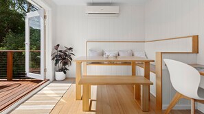 Enjoy a peaceful space with a large window offering a view of lush greenery, a dining area with a table and bench, and a potted plant.