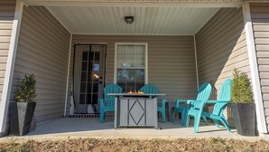 Une véranda couverte avec une table-brasero et des chaises turquoise.