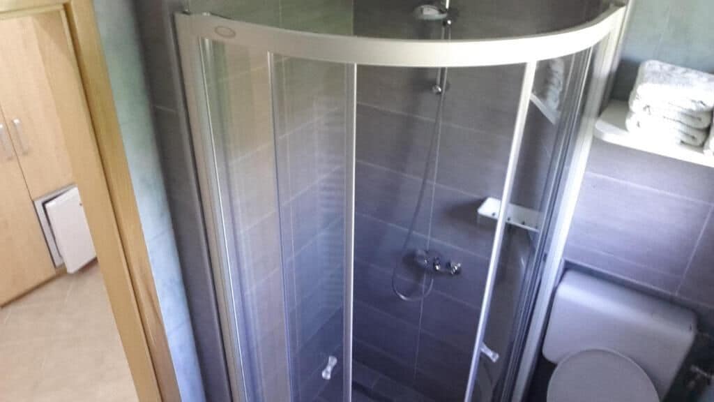 Un bagno con cabina doccia in vetro, un water e un lavandino.