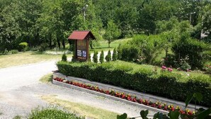 A rural road with a small wooden structure labeled "Hotel" and a signboard with amenities. - Lake House Plitvice (Plitvicka Jezera)