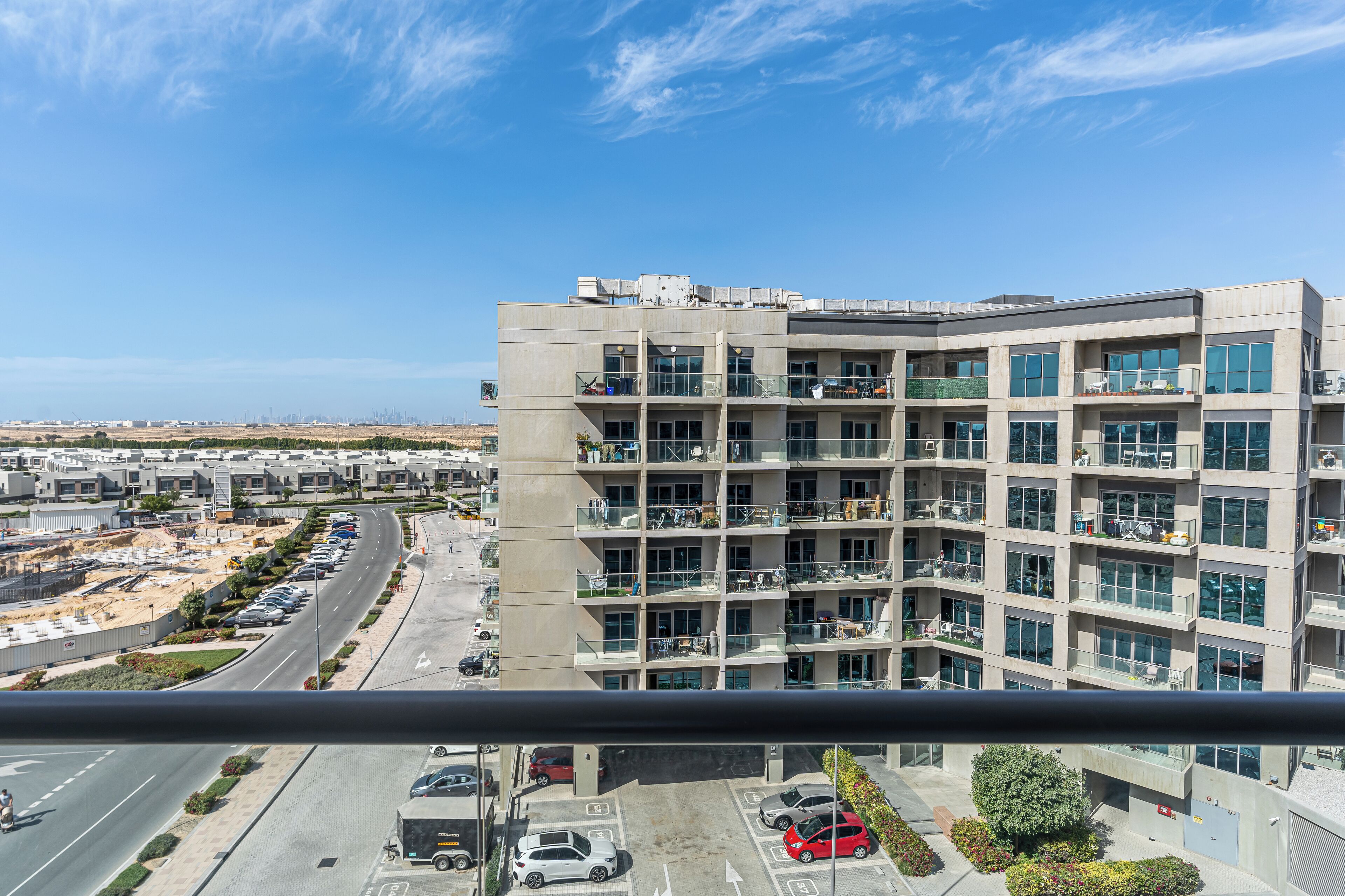 Un edificio residencial de varios pisos con balcones, estacionamiento y vistas despejadas del entorno.