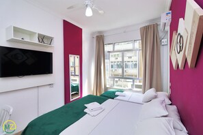 A hotel room with two beds, a flat-screen TV, a ceiling fan, a window with curtains, and a wall-mounted air conditioner. - PRADO XII (Rio de Janeiro)