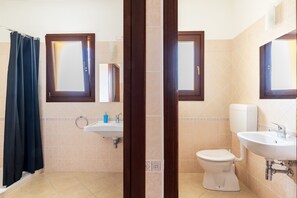 A bathroom with a shower, toilet, sink, and mirror.