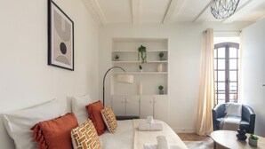Ein modernes Schlafzimmer mit Bett, Nachttischen, einer Couch, einem Schreibtisch und einem Stuhl. Ein Fenster mit Vorhängen und eine Pflanze stehen auf dem Schreibtisch.
