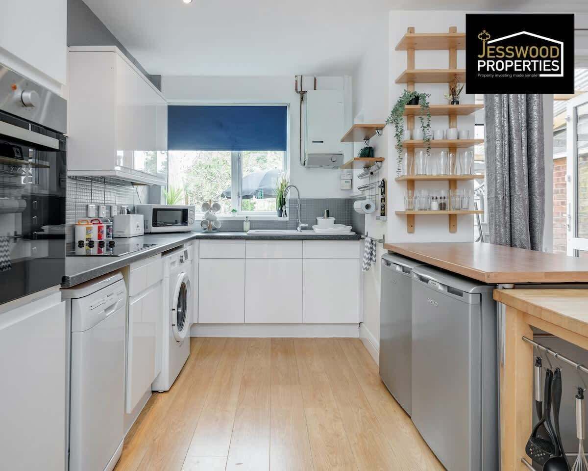 Een moderne keuken met witte kastjes, roestvrijstalen apparatuur en een houten vloer.