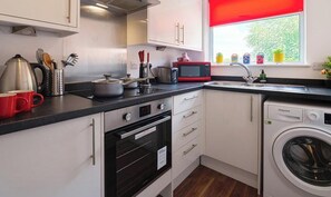 Eine kleine Küche mit Mikrowelle, Toaster, Spüle und Waschmaschine.