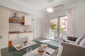 Eine moderne Küche mit Essbereich, einer Couch und Blick ins Freie.