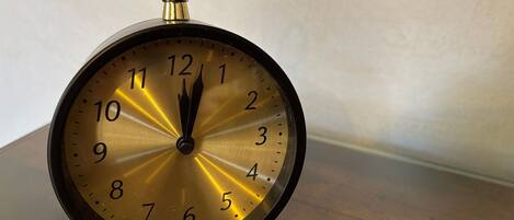 A vintage wall clock with a gold face and black hands, mounted on a wooden surface.