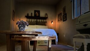 A wooden table with a vase of flowers in a room with a bed, a dresser, and framed pictures on the wall. - Loft Carrara (Val'Quirico)