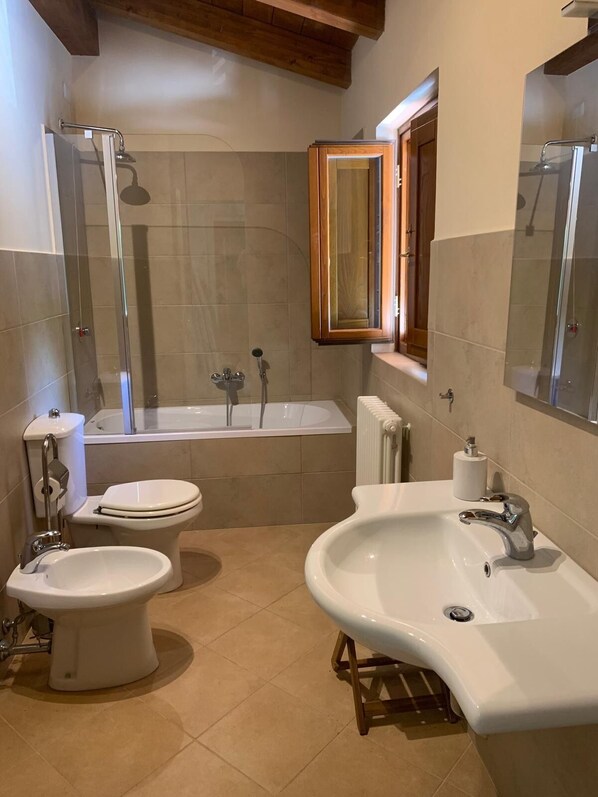 A modern bathroom with a bathtub, two toilets, a sink, and a mirror. - Beautiful family villa with private pool and wonderful mountain views near Barga (Sommocolonia)