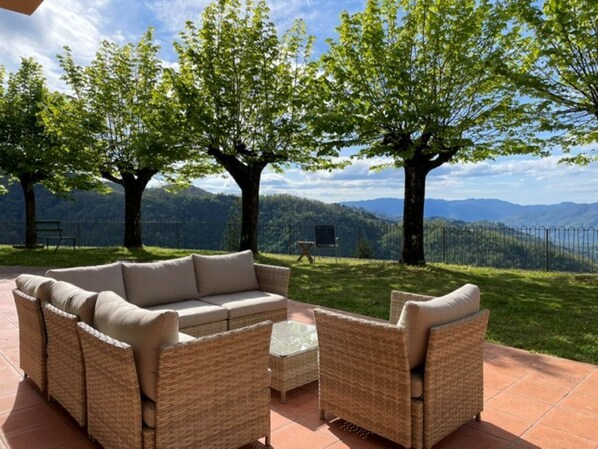 An outdoor seating area with wicker furniture and a view of mountains. - Beautiful family villa with private pool and wonderful mountain views near Barga (Sommocolonia)