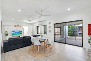 A modern living room with a sofa, dining table, chairs, and a TV.