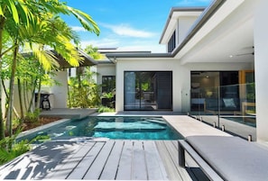 A modern house with a swimming pool, outdoor seating, and lush greenery.