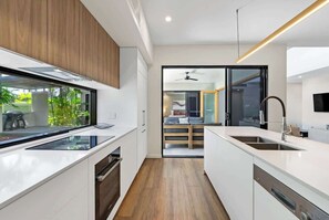 Una cucina moderna con mobili bianchi, forno integrato e un'ampia finestra.