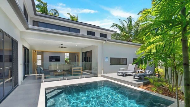 A modern house with a swimming pool, glass doors leading to a living area, and outdoor seating. - Sea Mist—Poolside Oasis near Palm Cove Beachfront (Palm Cove)