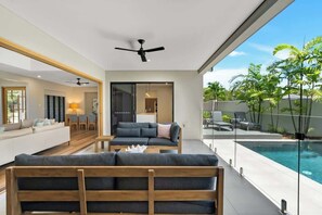 Una sala de estar moderna con un sofá, una mesa de centro y vista a una piscina.