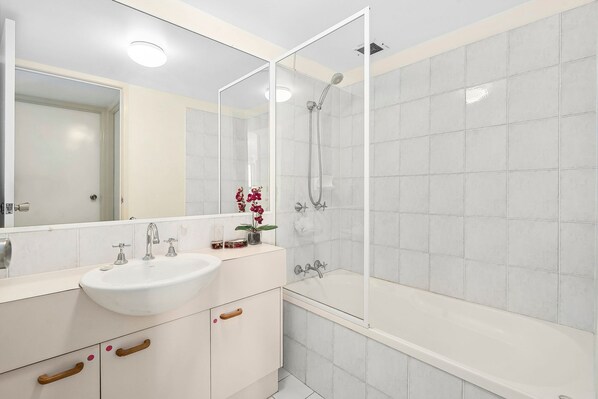 Ein modernes Badezimmer mit einem weißen Waschbecken, einem Waschtisch und einer Duschkabine.
