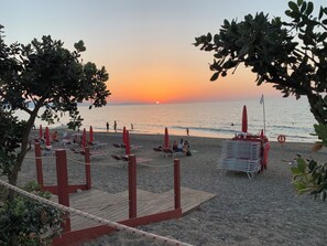 Egy strand, ahol napozóágyak és napernyők találhatók, emellett van egy mentőtorony és egy fából készült terasz is.