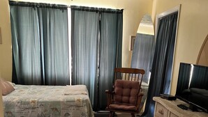 A room with two beds, a wooden rocking chair, a dresser, and a television.