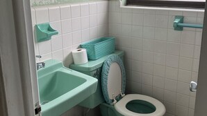 A bathroom with a toilet, sink, and window.