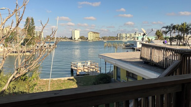 A waterfront view with a dock, wooden deck, and buildings in the background.